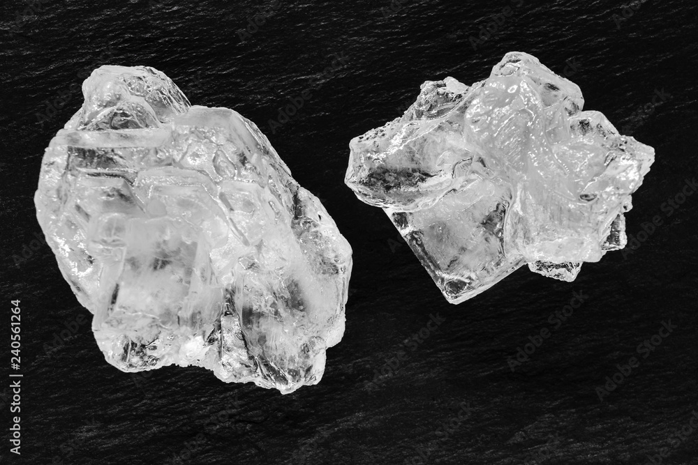 Top view of two sugar or salt crystals placed on black stone background surface Top view of two sugar or salt crystals placed on black stone background surface