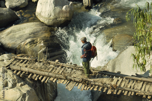 A peasant is walking along the bridge over the river. photo