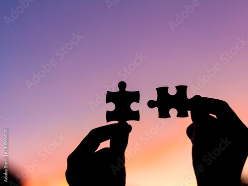Silhouettes of hands holding piece of red jigsaw puzzle. teamwork concept - Image