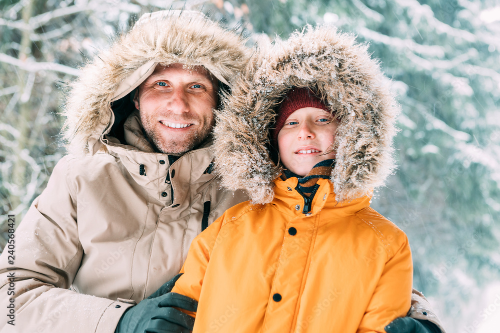 Father and son dressed in Warm Hooded Casual Parka Jacket Outerwear walking  in snowy forest cheerful smiling faces portrait. Father and son relatives  and winter outfit concept image. Stock Photo | Adobe