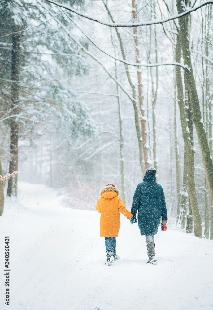 Mother and son walking in snowy forest. Mother and son relatives concept image.