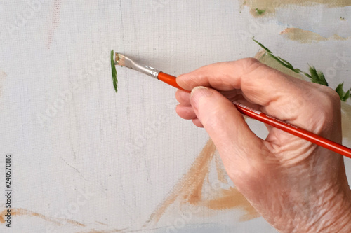  hand of an elderly person paints a picture with a brush