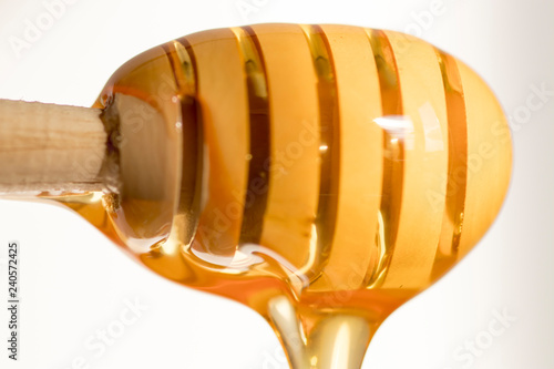Honey flows from honey spoon in wood