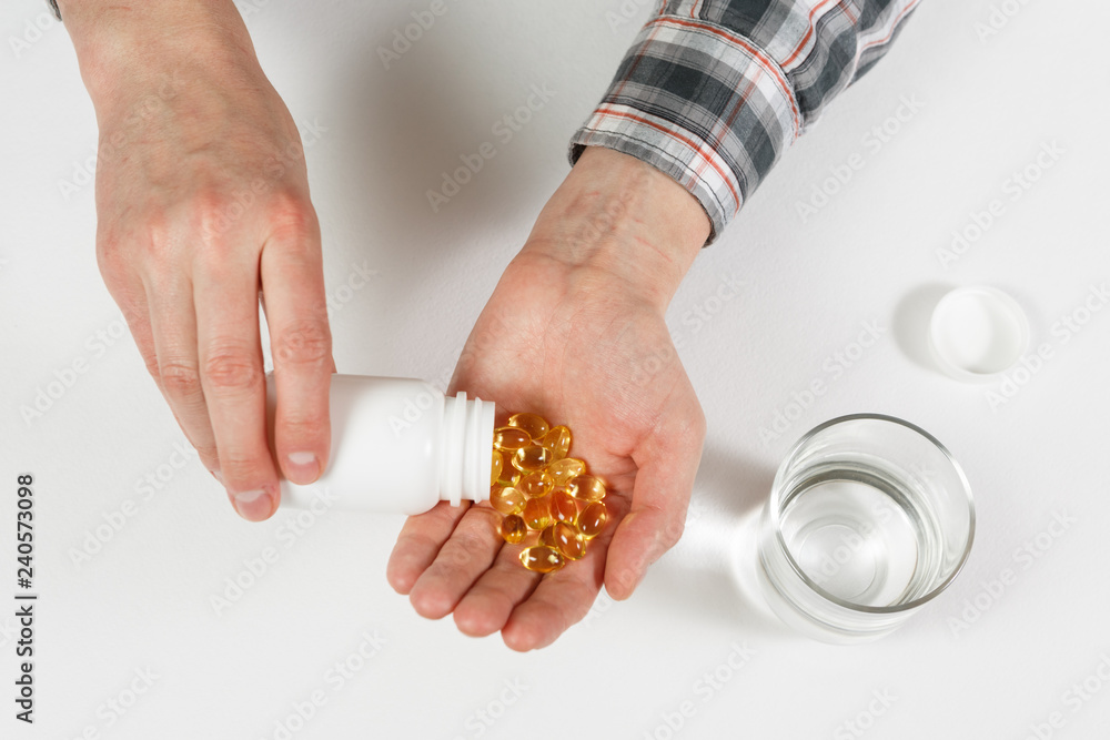 Obraz premium Man hand holds yellow medication capsules of omega 3