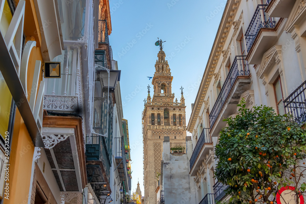 View of Giralda tower of Cathedral of Saint Mary of the See (Seville Cathedral) through a narrow street