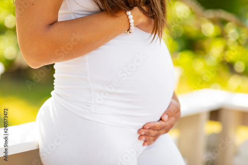 Close-up of pregnant woman standing outdoor holding hands on belly