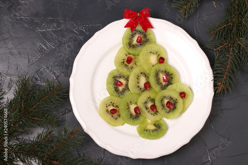 Christmas tree made from kiwi and pomegranate,  creative idea for Christmas and New Year festive dishes, fruit snack for children