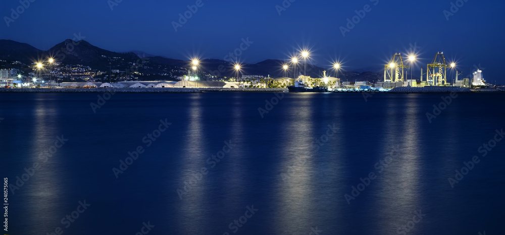 view of Malaga's port, with lights reflecting in the water surface at blue hour, Spain view of Malaga's port, with lights reflecting in the water surface at blue hour, Spain