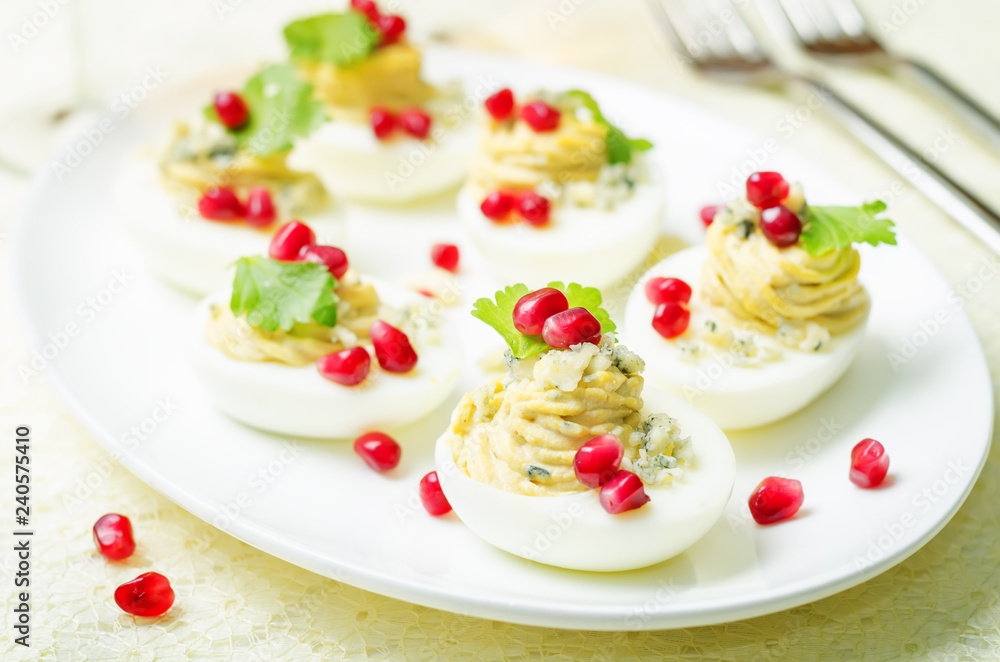 Blue cheese deviled eggs with pomegranate and fresh parsley leaves