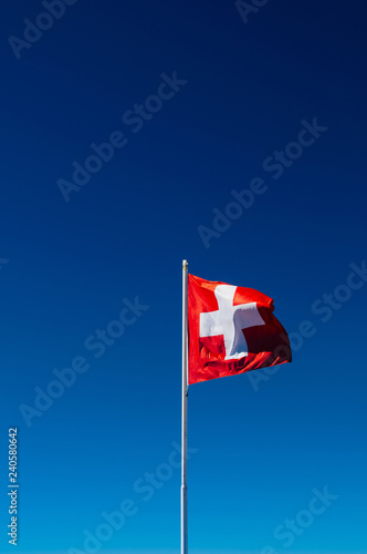 Swiss flag - Switzerland flag against bright blue sky