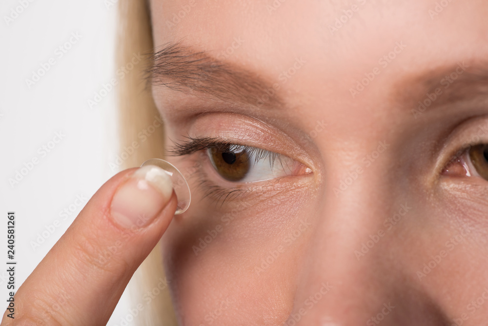 Fototapeta premium A girl with brown eyes wears a contact lens for vision