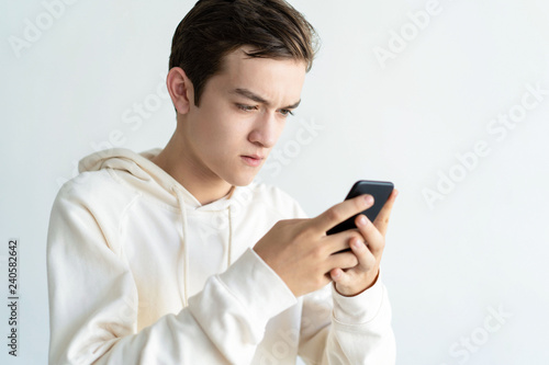 Focused teen boy holding and using smartphone. Technology concept. Isolated front view on white background.