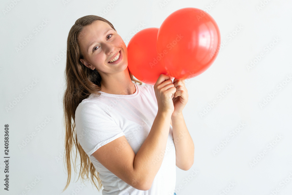 Smiling lovely woman holding two red balloons. Playful lady looking at camera. Party concept. Isolated front view on white background. Smiling lovely woman holding two red balloons. Playful lady looking at camera. Party concept. Isolated front view on white background.