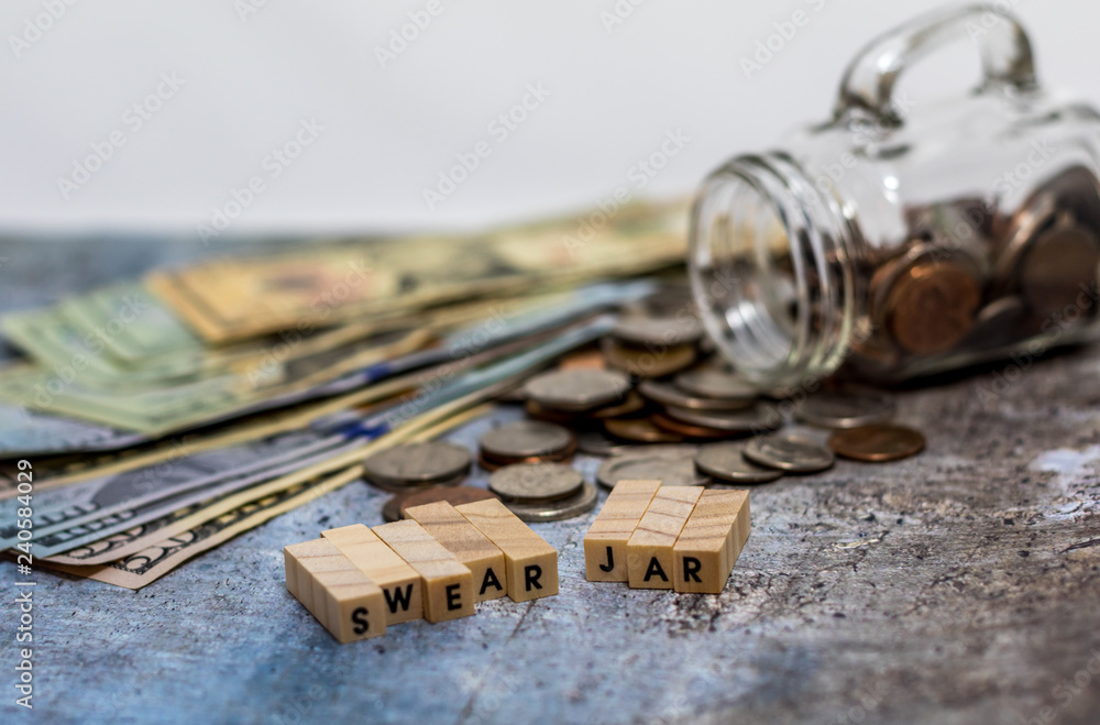 Swear Jar challenge concept with glass jar filled with coins, simple background Swear Jar challenge concept with glass jar filled with coins, simple background