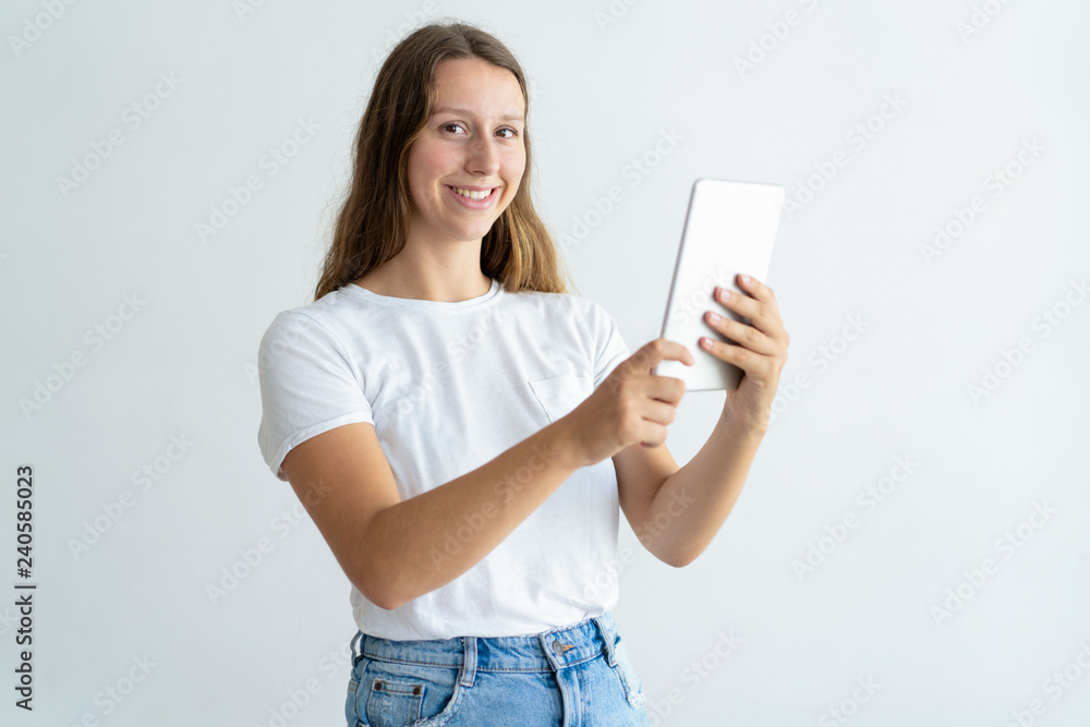 Smiling young woman using tablet computer. Pretty lady browsing on tablet and looking at camera. Technology concept. Isolated view on white background. Smiling young woman using tablet computer. Pretty lady browsing on tablet and looking at camera. Technology concept. Isolated view on white background.