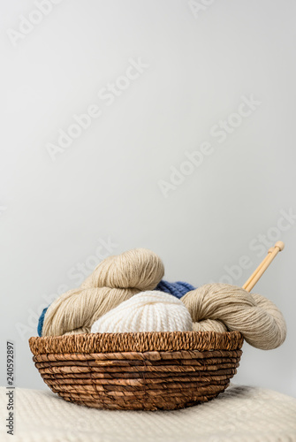 close up view of yarn clews in wicker basket on grey backdrop
