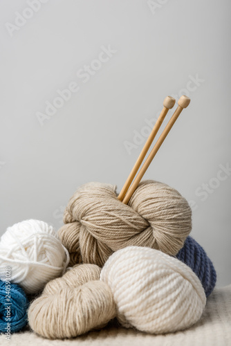 close up view of knitting needles in yarn clews on grey background