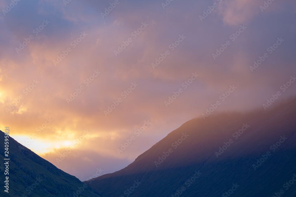 low sun rays shone across a mountain at sunset