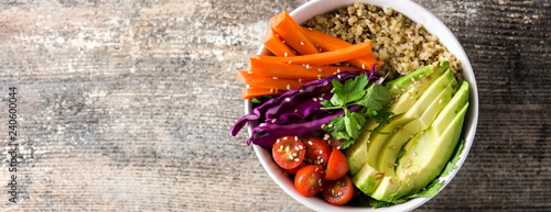 Vegan Buddha bowl with fresh raw vegetables and quinoa on wooden table. Panoramic view. Copyspace