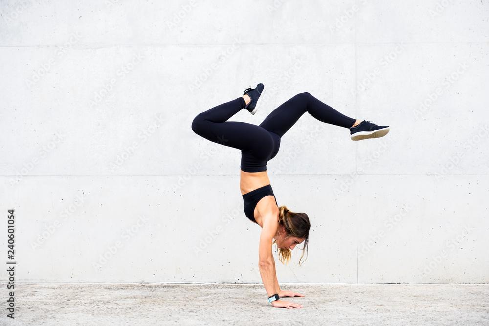 Athlete doing handstand in front of white wall Athlete doing handstand in front of white wall