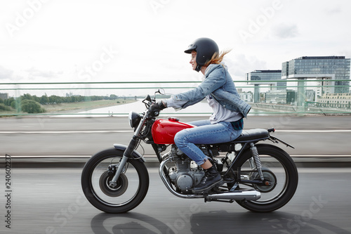 Germany, Cologne, young woman riding motorcycle on bridge