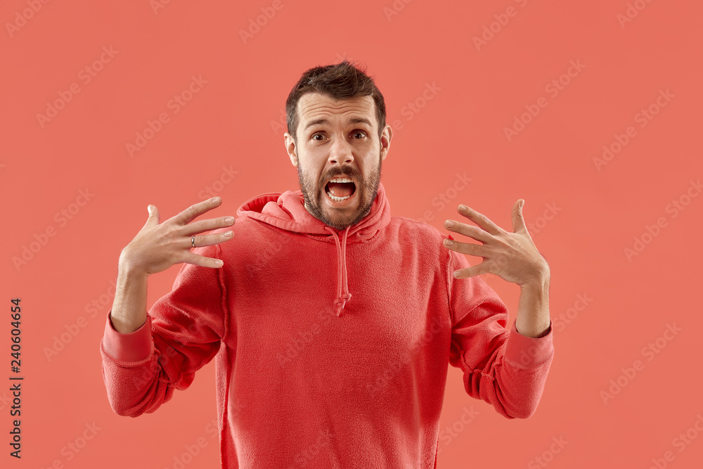 Wow. Attractive male half-length front portrait on coral studio backgroud. Young emotional surprised bearded man standing with open mouth. Human emotions, facial expression concept. Trendy colors Wow. Attractive male half-length front portrait on coral studio backgroud. Young emotional surprised bearded man standing with open mouth. Human emotions, facial expression concept. Trendy colors