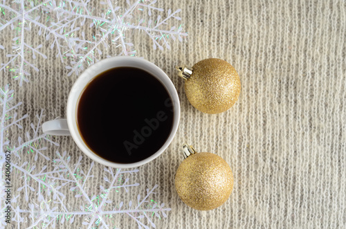 A Cup of coffee , decorated snowflakes and two pair Christmas golden ballson a light wool sweater.Winter concept.