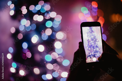 Man holding a phone and taking a picture of a Christmas tree