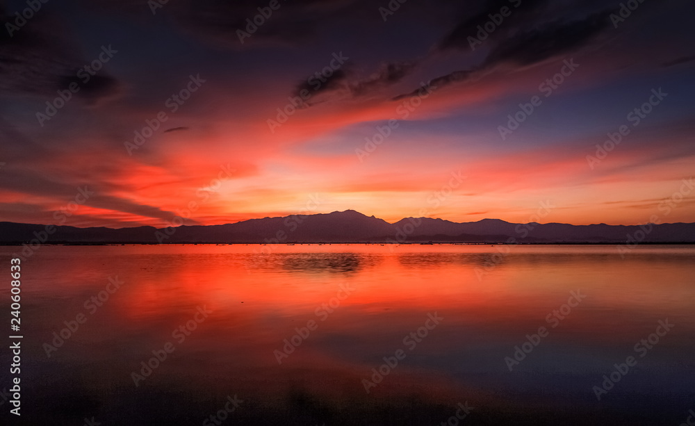 Lake view evening of colorful red cloudy sky above the hill with reflection on the water, sunset at Kwan Phayao Lake, Phayao Province, northern of Thailand.