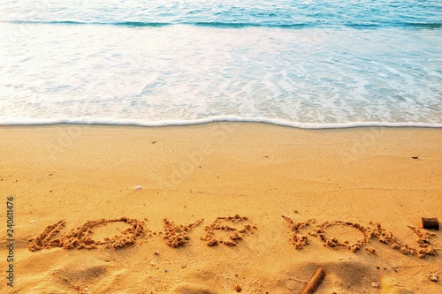 Valentine's Day concept, the word love you writing on sand beach with blue waves ocean.