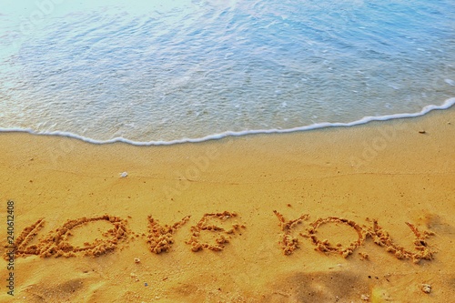 Valentine's Day concept, the word love you writing on sand beach with blue waves ocean. © Rujirat