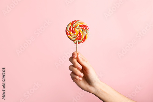 Woman holding yummy candy on color background