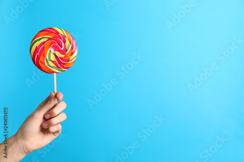 Woman holding yummy candy on color background. Space for text