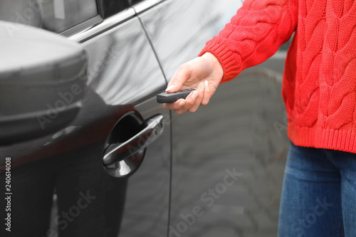 Closeup view of woman opening car door with remote key