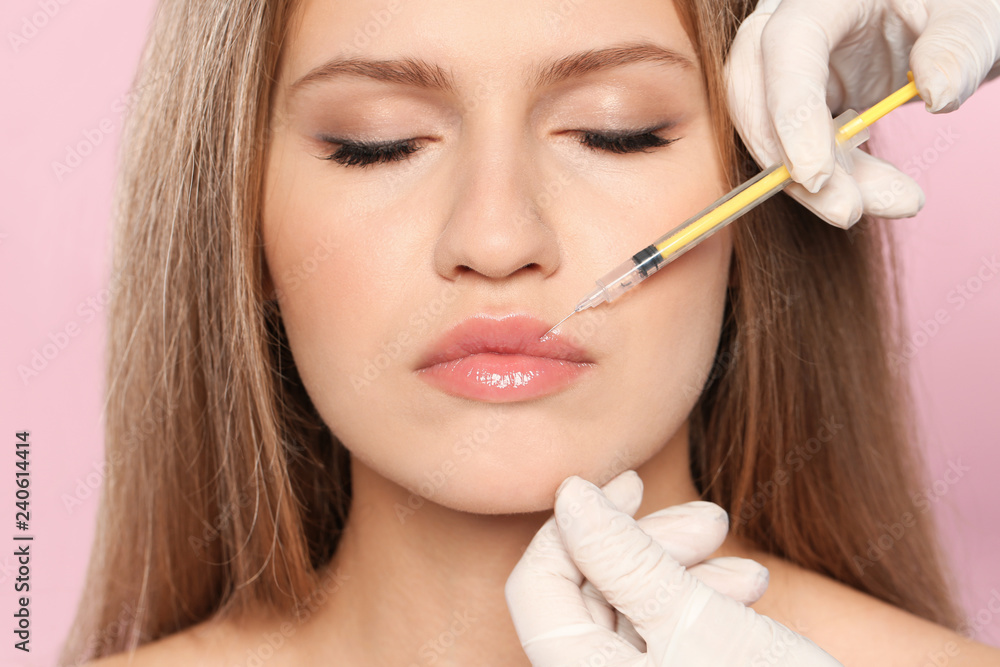 Young woman getting lips injection on color background, closeup. Cosmetic surgery Young woman getting lips injection on color background, closeup. Cosmetic surgery