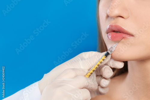 Young woman getting lips injection on color background  space for text. Cosmetic surgery