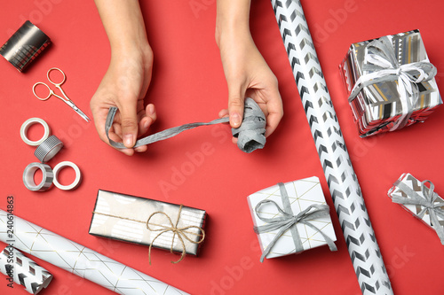 Woman decorating gift box on color background, top view