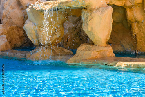 Small waterfall with turquoise water in the hotel pool