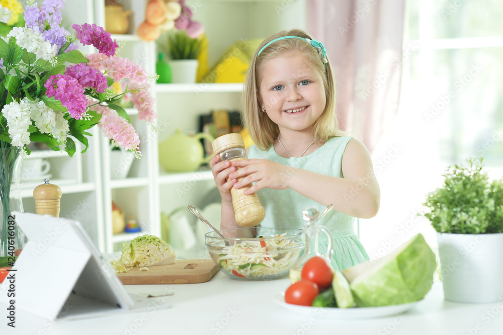 Cute little girl spicing salad on kitchen table Cute little girl spicing salad on kitchen table