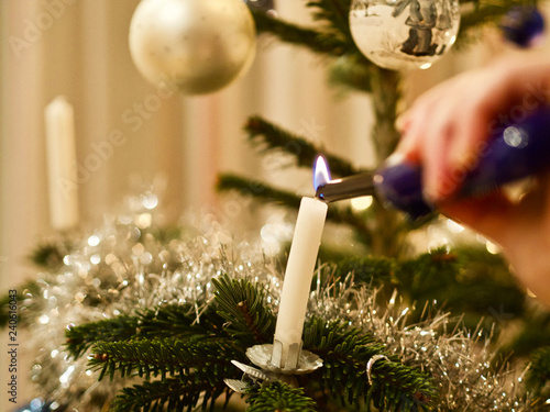 Eine Person zündet zu Weihnachten Kerzen auf dem Christbaum an