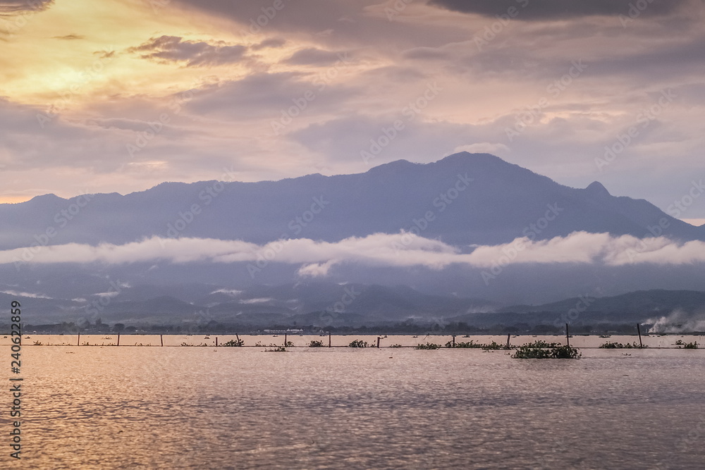 Beautiful lake view evening of cloudy sky with the mist moving in the sky background, sunset at Kwan Phayao, Phayao Province, northern of Thailand.