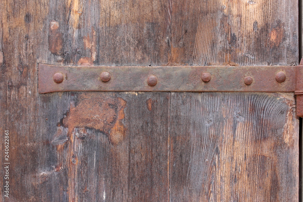 Old wooden door and metal hinge, background texture, worn brown aged tones Old wooden door and metal hinge, background texture, worn brown aged tones