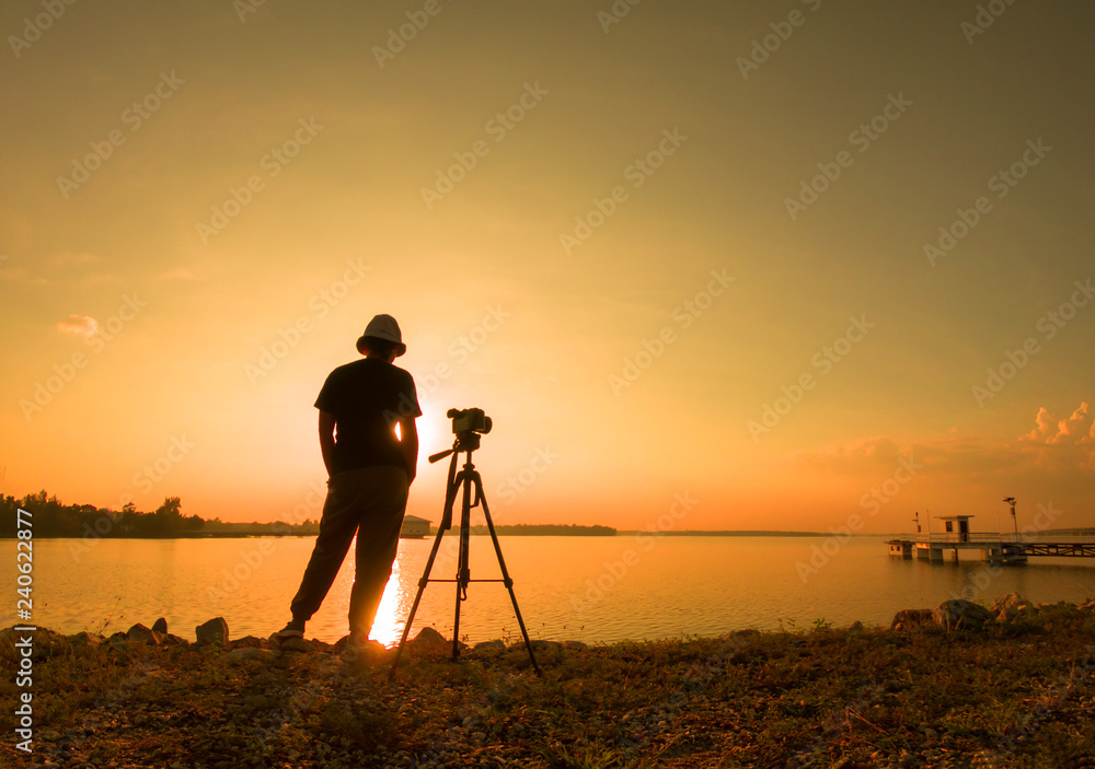 silhouette of young woman photographer,  of landscape at sunset.