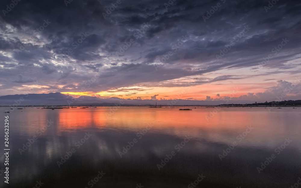 Beautiful lake view evening of cloudy sky with colorful of red light in the sky background, sunset at Kwan Phayao, Phayao Province, northern of Thailand.