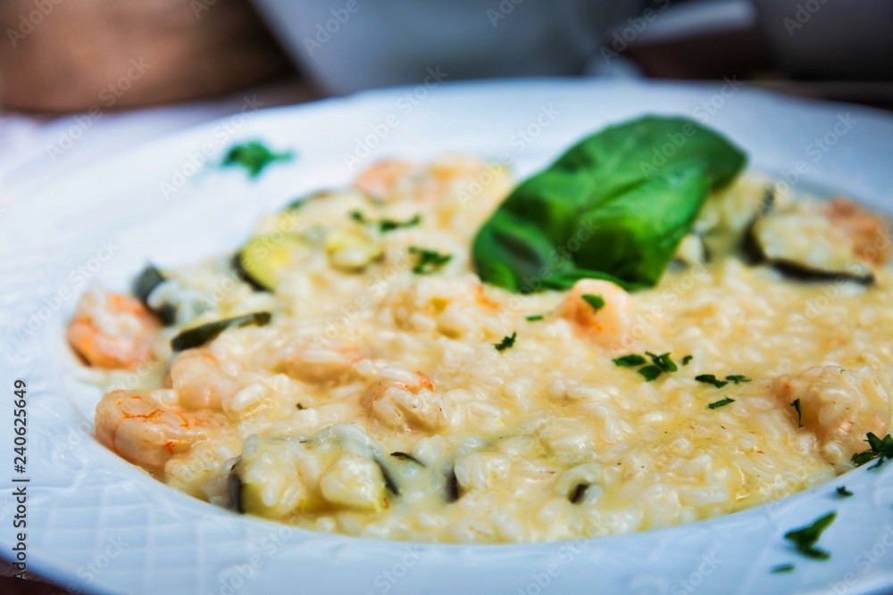 Tasty risotto with Shrimp, fresh herbs vegetables on a white plate Tasty risotto with Shrimp, fresh herbs vegetables on a white plate