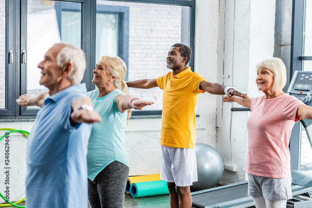 © LIGHTFIELD STUDIOS - selective focus of multiethnic senior athletes synchronous doing exercise at sports hall © LIGHTFIELD STUDIOS - selective focus of multiethnic senior athletes synchronous doing exercise at sports hall