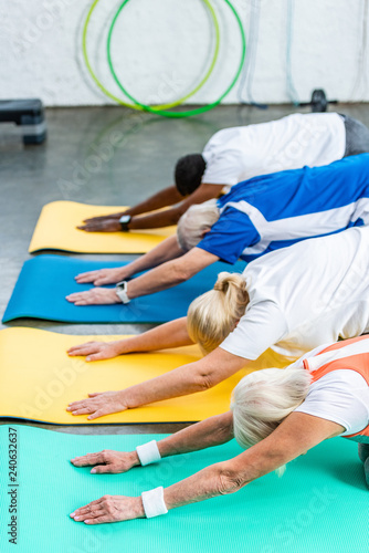 side view of multicultural senior athletes synchronous exercising on fitness mats at gym © LIGHTFIELD STUDIOS