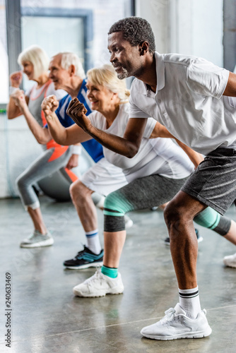 african american sportsman synchronous exercising with friends at sports hall © LIGHTFIELD STUDIOS
