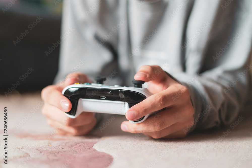 young boy lying on the floor carpet and playing video game at home f