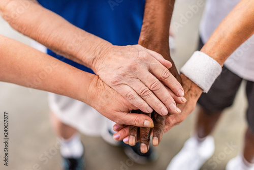 partial view of senior multiculutral sportspeople putting hands together at sports hall